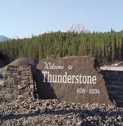 Welcome to Thunderstone sign at the quarry entrance, with forest and Rocky Mountain peaks behind
